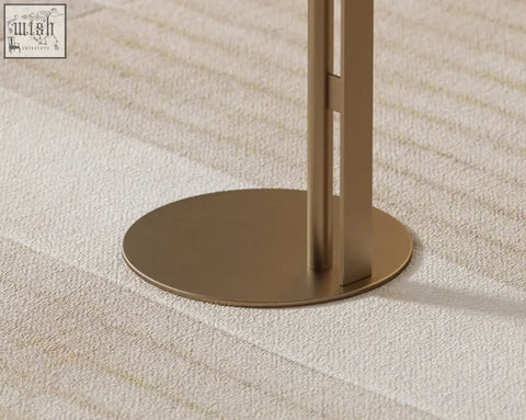 A sleek minimalist floor lamp with brushed gold metal base standing next to the bagley coffee table stainless steel