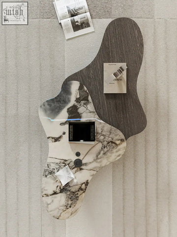 Organic-shaped baines marble coffee table with two-tone marble top and black circular controls in a sleek design