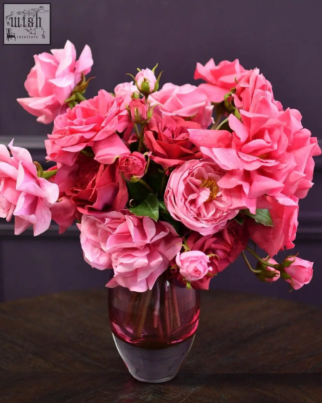 A mouth blown dutz collection ball vase hoola in fuchsia with a vibrant bouquet of pink roses in translucent glass