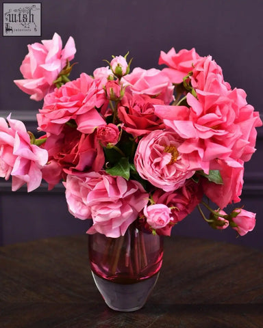 A mouth blown dutz collection ball vase hoola in fuchsia with a vibrant bouquet of pink roses in translucent glass