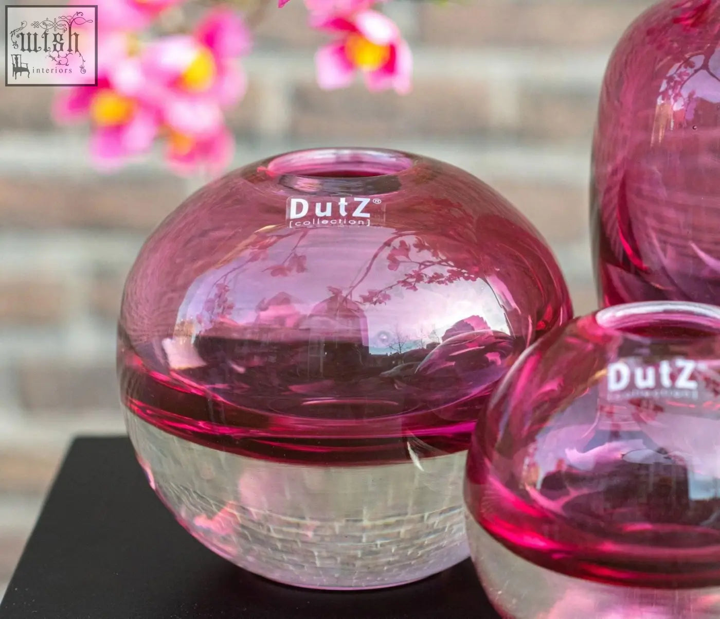 Vibrant pink mouth blown glass ball vase with clear textured base and dutz collection logo etched on surface