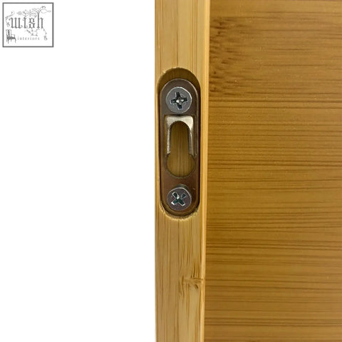 A sleek brushed metal door latch with matte finish on a solid wood bamboo wall cabinet for kitchen storage