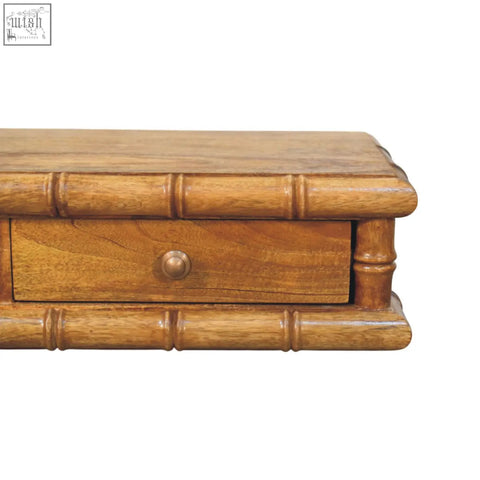 Light brown bamboo wall-mounted console with vertical grooves and single drawer with round brass knob on wooden desk