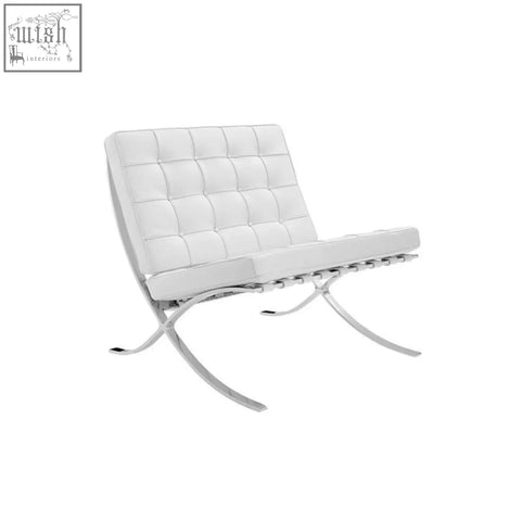 White tufted real leather barcelona chair with chrome x shaped legs next to matching stool in modern style
