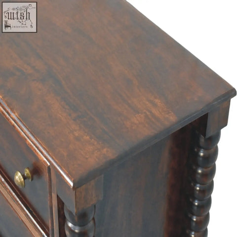 Dark brown wooden nightstand with polished finish and turned spindle legs in winewood oak tone with antique brass knobs