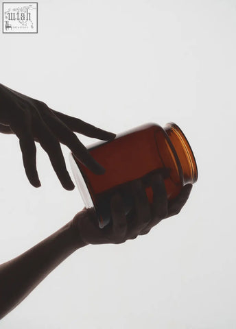 A translucent amber glass storage jar with a smooth rounded body perfect for holding cotton pads