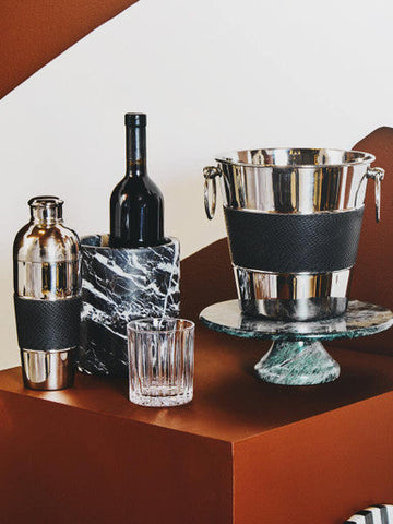 Silver ice bucket with black textured band and dual handles on green marble pedestal in beaufort set crystal large tumblers