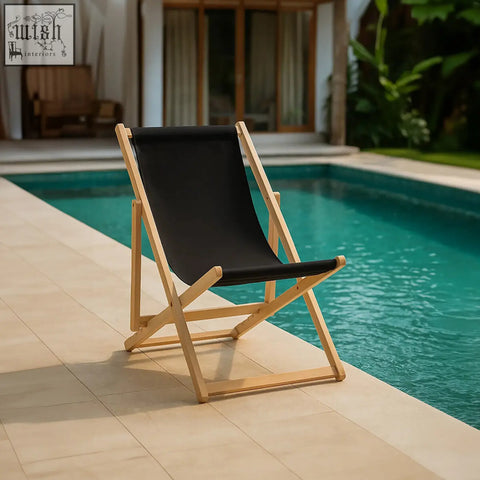 Black deck chair with light wood frame made of canvas fabric placed poolside perfect for outdoor lounging