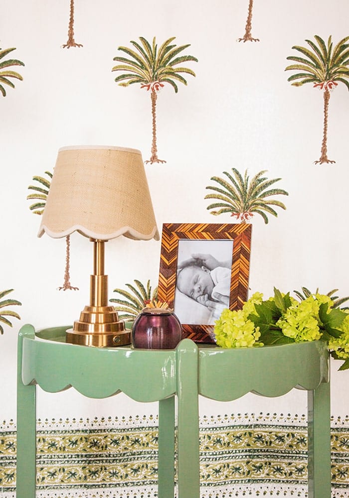 A gold-toned table lamp with a beige scalloped fabric shade on a mint green side table from beautifully sweet scallop lampshade