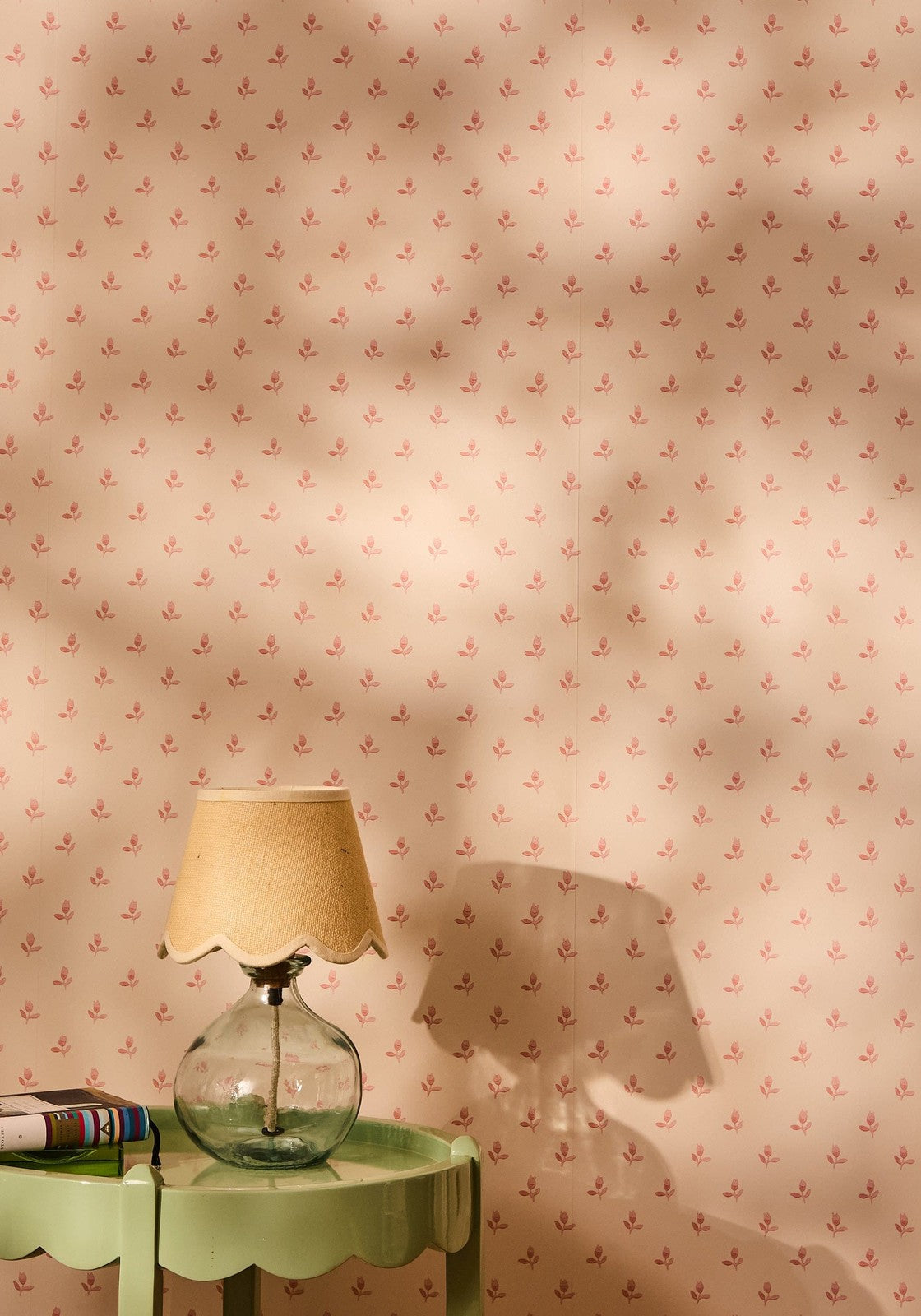 A beautifully sweet scallop lampshade beige fabric shade on a clear glass table lamp sitting on a green side table