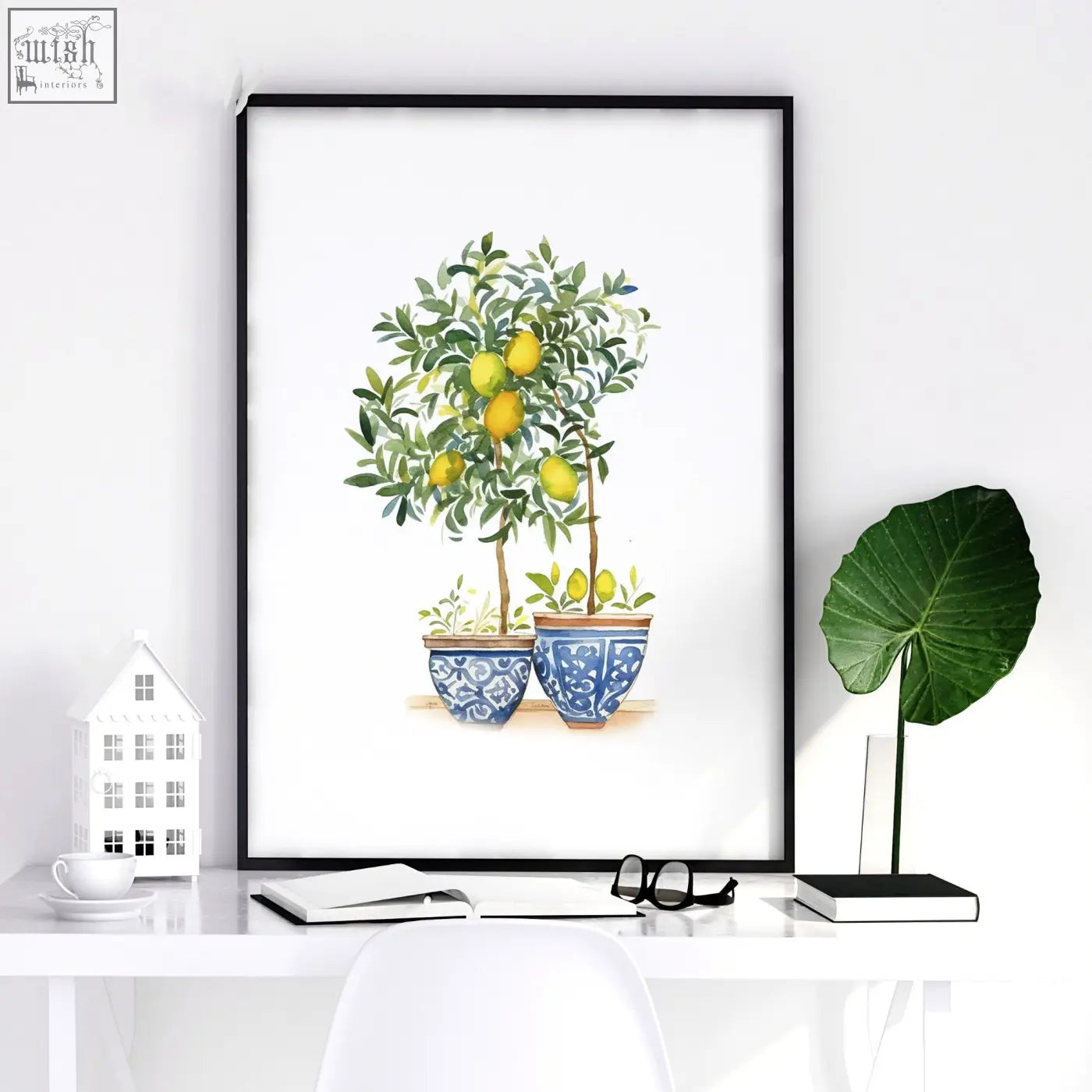 A framed french country bedroom picture showing two blue and white ceramic pots with a lemon tree and green leaves