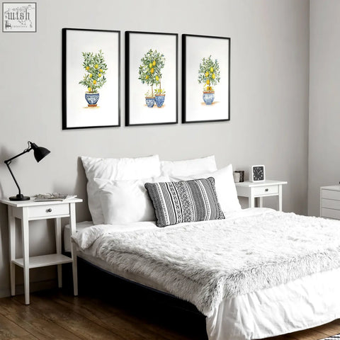 Three framed french country bedroom pictures of lemon tree prints in blue and white ceramic pots above a bed
