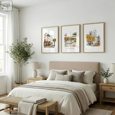 Beige upholstered bed with matching pillows and neutral duvet below parisian autumn travel art bedroom wall pictures set of 3