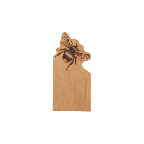 A light brown wooden bookmark shaped like michigan with a black engraved bee on a small framed oak serving board