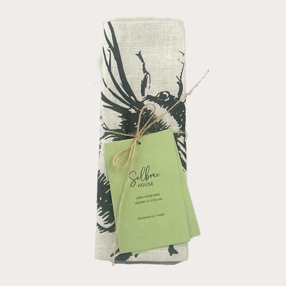 A rolled black and white stag print linen napkin tied with twine and labeled by selfrae house set of 2