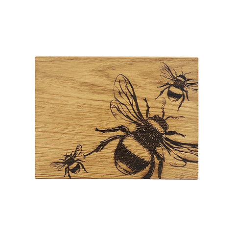 Rectangular british oak bar board with detailed black bee engravings on a light natural wood surface