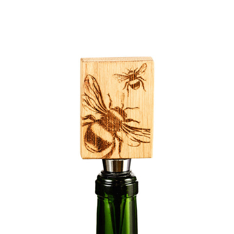 A rectangular natural light british oak bottle stopper with intricate bee engravings called bee oak bottle stopper