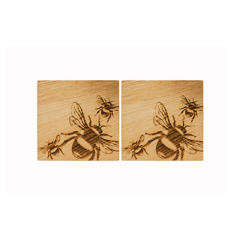 Two light british oak coasters with dark brown engraved bee designs perfect for stylish tabletops