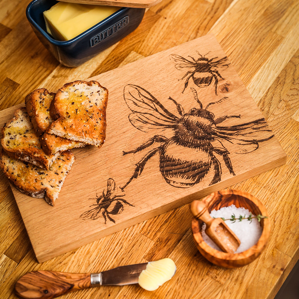 A light brown oak serving board with intricate bee oak engravings perfect for serving and cheese platters