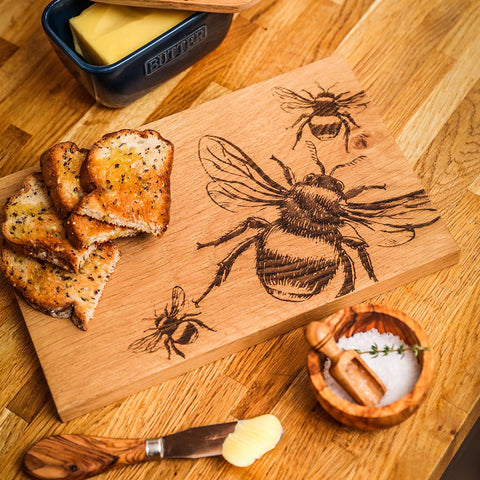 A light brown oak serving board with intricate bee oak engravings perfect for serving and cheese platters