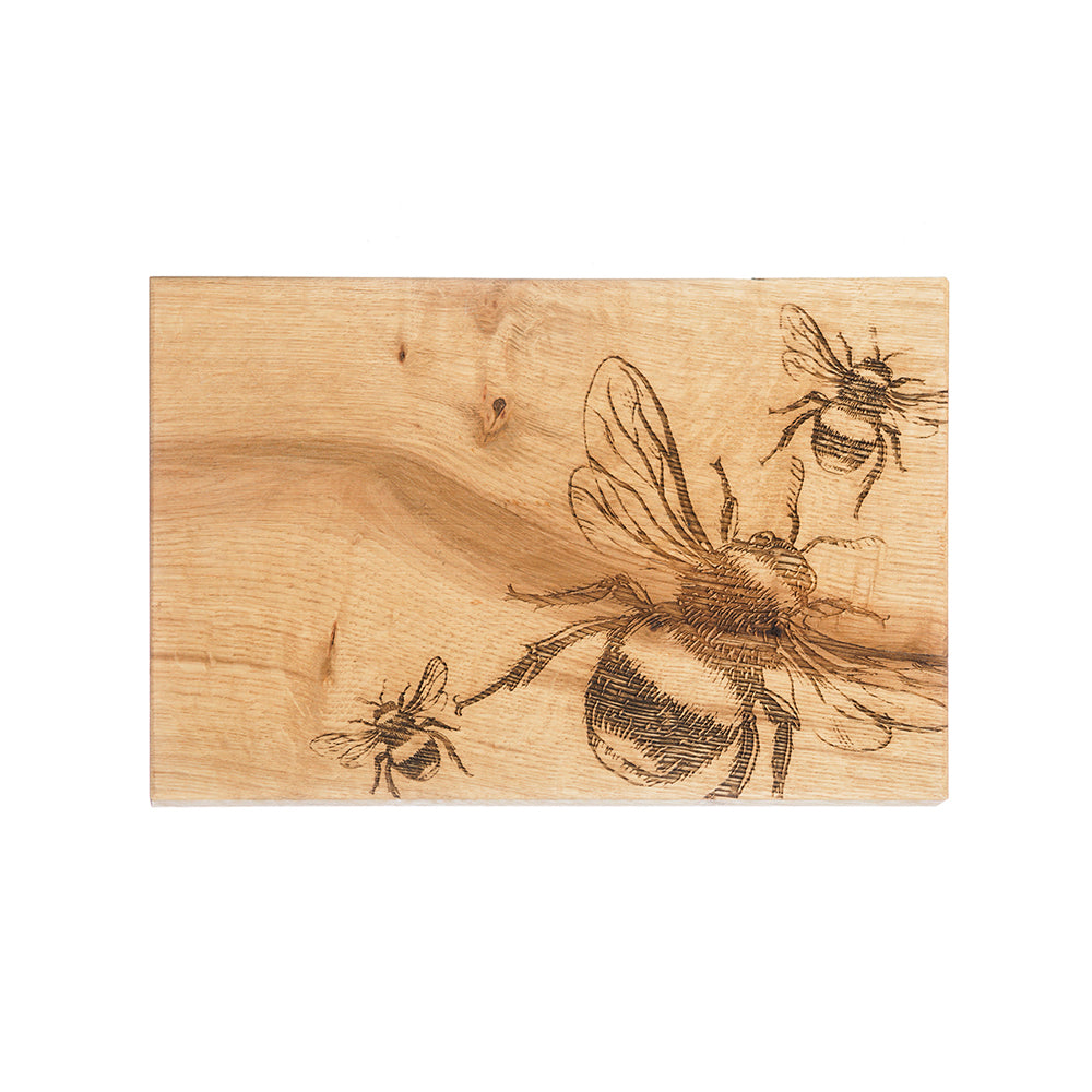 Rectangular light-colored oak serving board with intricately burned bee oak illustrations in dark brown tones