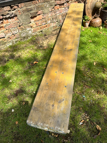 Weathered yellow wooden beer festival fold up bench with visible grain and nail holes perfect for garden seating