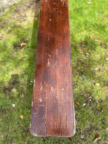 Worn wooden ski with dark brown finish and nail holes seen as part of beer festival fold up bench garden furniture