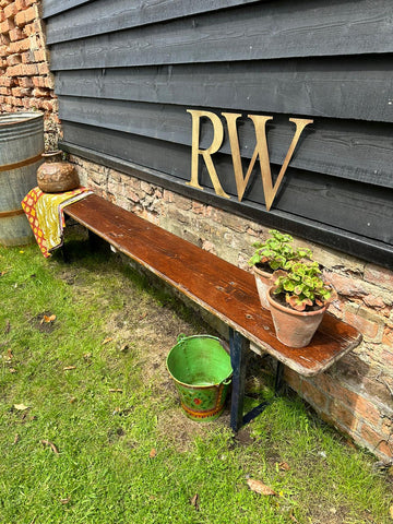A rustic reddish-brown wooden beer festival fold up bench with dark metal legs perfect for garden or hallway seating