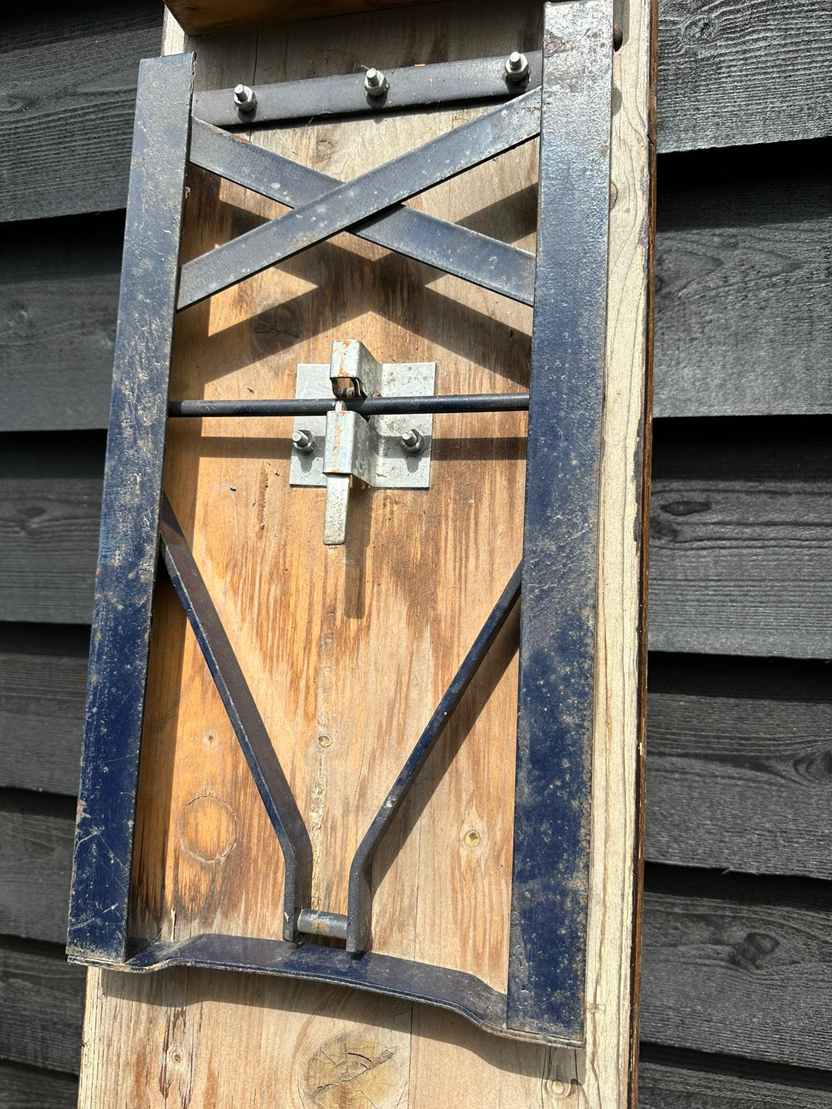 Rustic wooden gate with black metal frame and latch shown behind beer festival fold up bench for garden seating