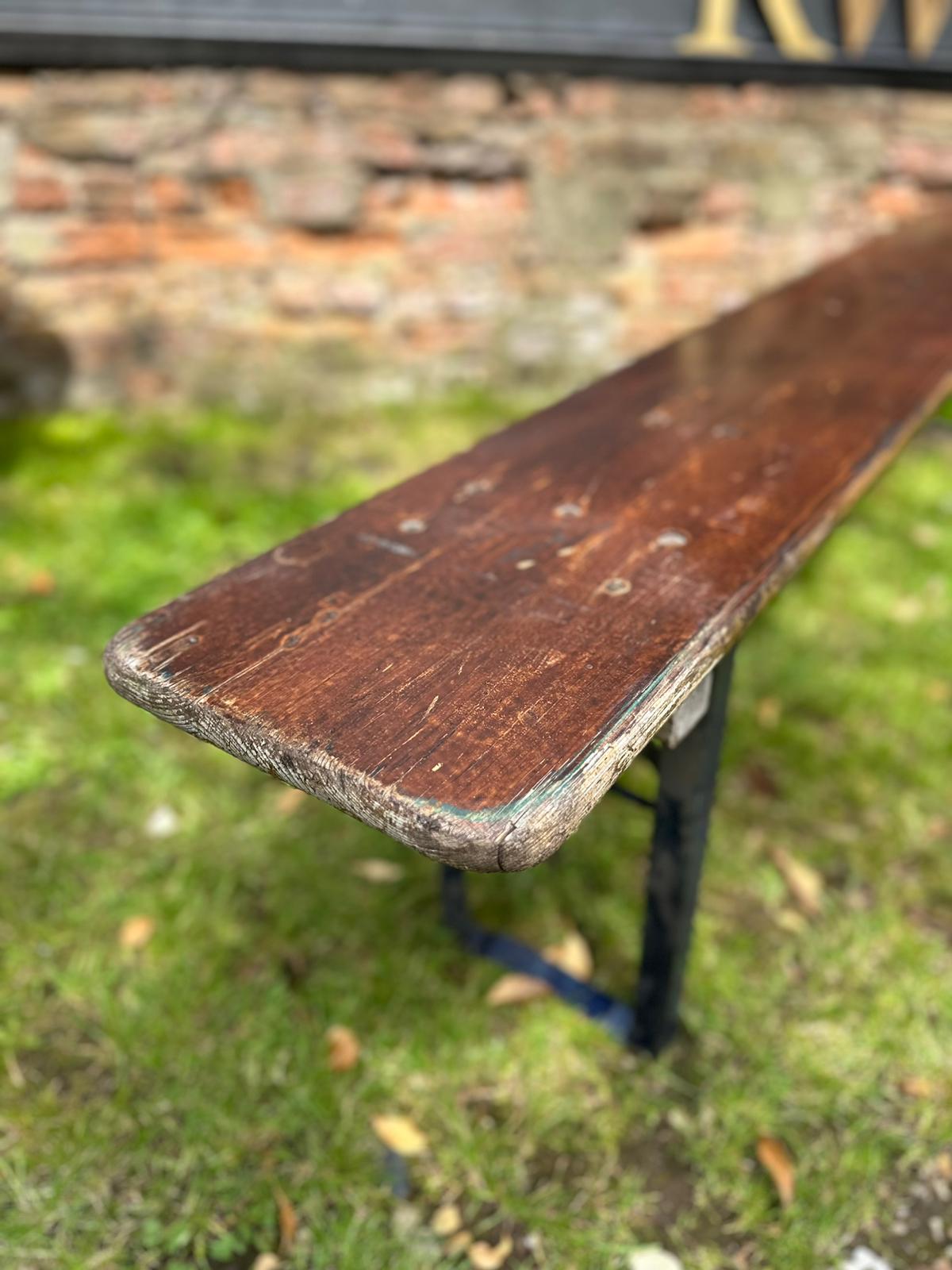 A weathered dark brown wooden beer festival fold up bench with rustic chipped finish perfect for garden seating