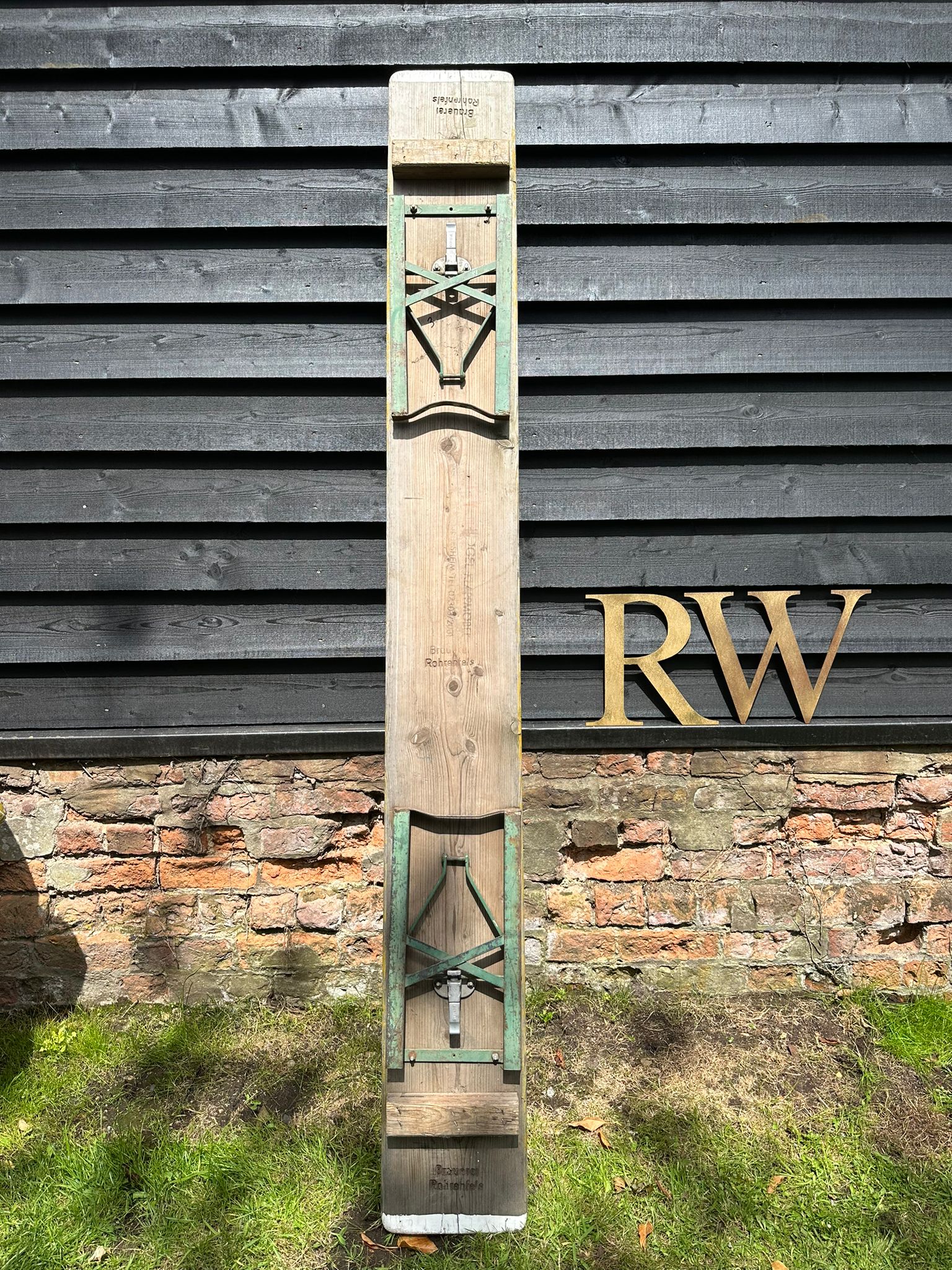 A vintage wooden beer festival fold up bench with green metal brackets and a white marker for garden seating