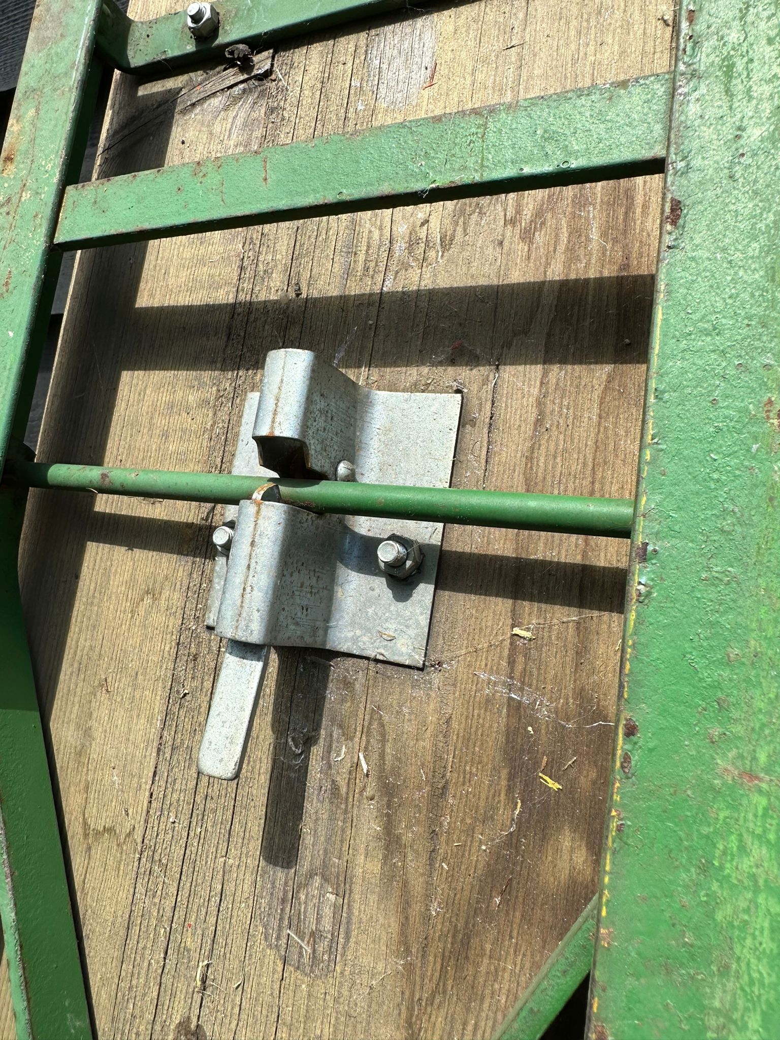 Green metal gate latch securing weathered wooden panel on the back of a beer festival fold up picnic bench