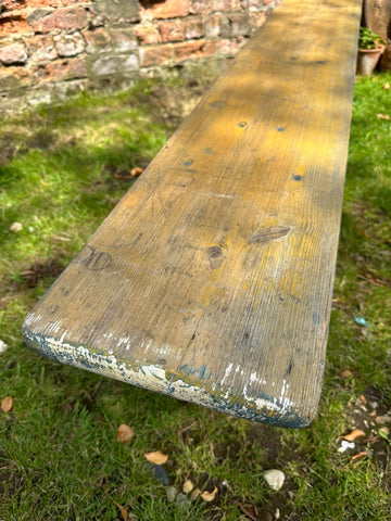 Weathered wooden beer festival fold up bench with yellowish brown finish and chipped white paint for garden seating