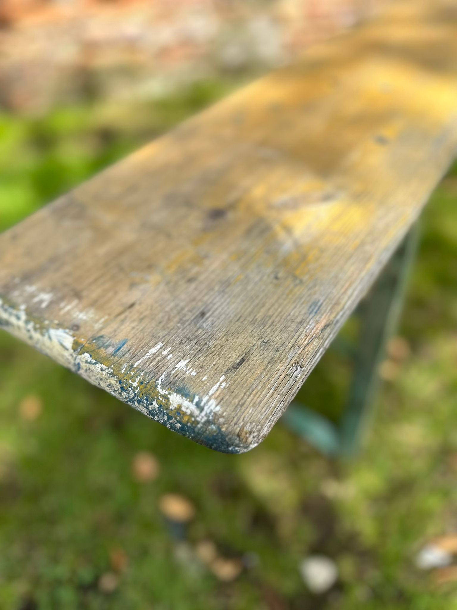 Worn wooden beer festival fold up bench with peeling paint and visible grain perfect for garden seating