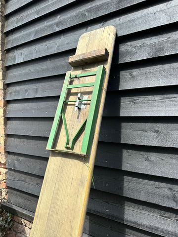 Vintage wooden ironing board with green metal frame and silver latch leaning against dark gray wall for beer festival use