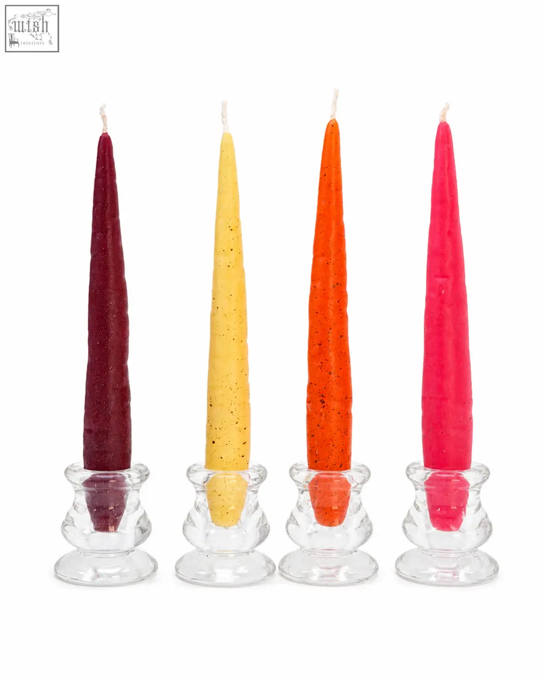 Four slender beeswax taper candles in maroon yellow orange and pink with speckled texture in clear glass holders