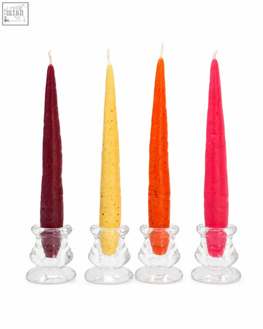 Four slender beeswax taper candles in maroon yellow orange and pink with speckled texture in clear glass holders