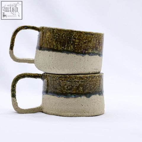 Two stacked beige grande handmade milled stoneware mugs with textured earthy green and beige glaze