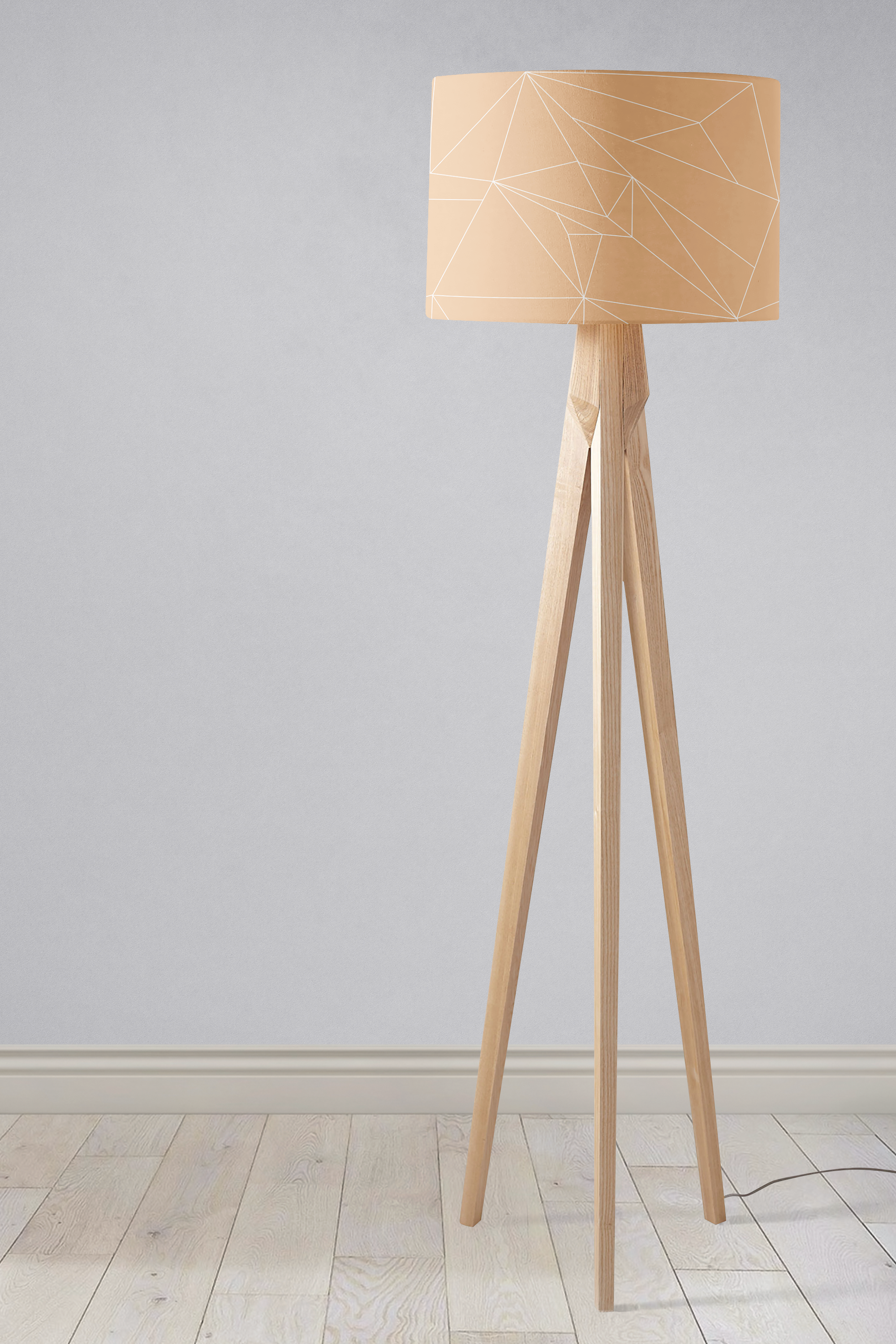 Beige minimalist lampshade with geometric pattern on a table lamp featuring a tripod wooden base