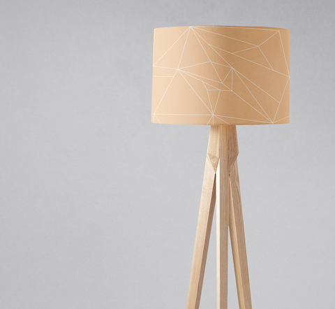 Beige minimalist lampshade with geometric pattern mounted on light wood tripod table lamp base