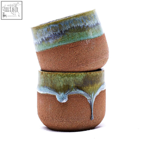 Two stacked beige picollo handmade ceramic espresso mugs with earthy brown texture and vibrant green-blue glaze drips