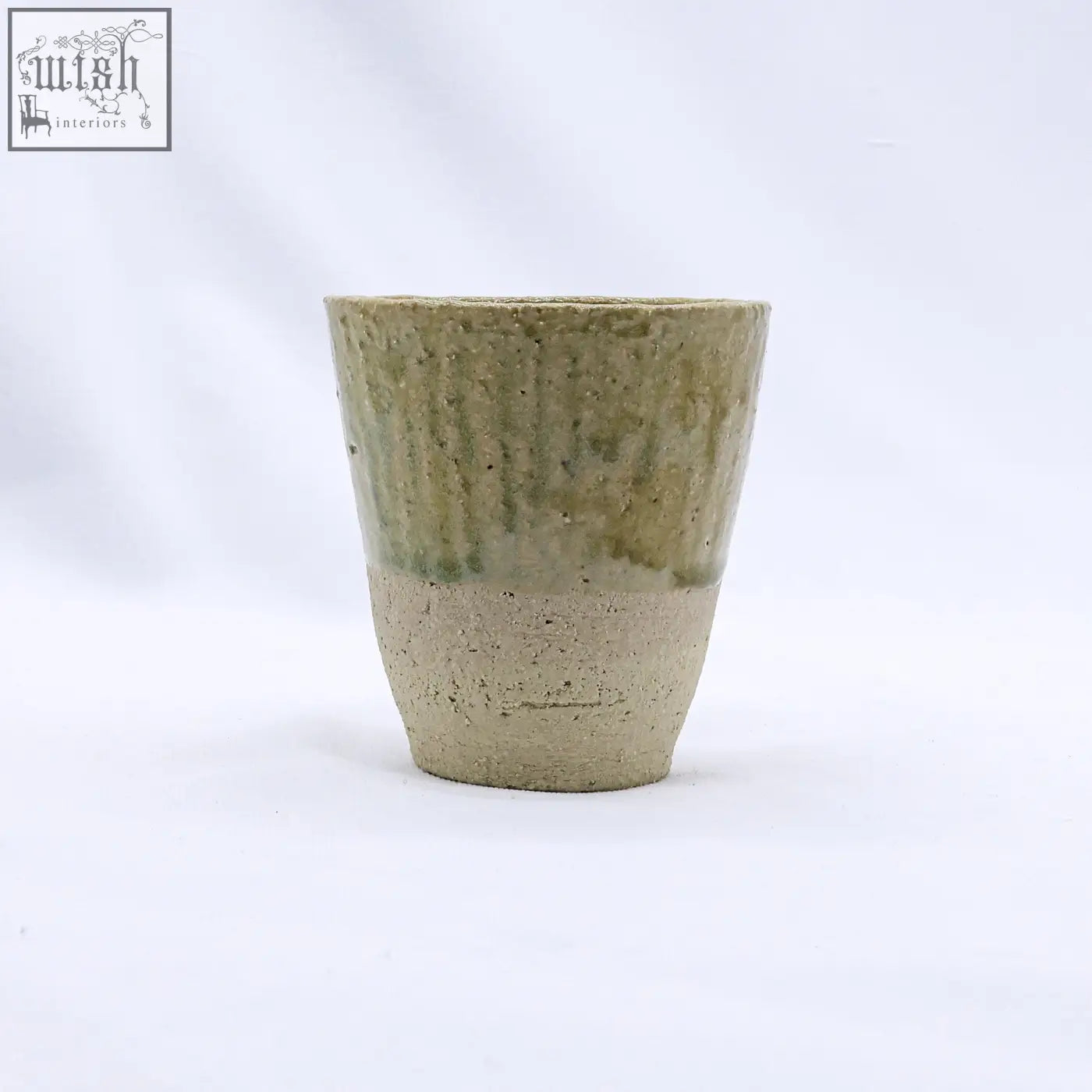 Beige quadra milled stoneware tall ceramic cup with earthy green glaze and unglazed clay base handcrafted rustic design