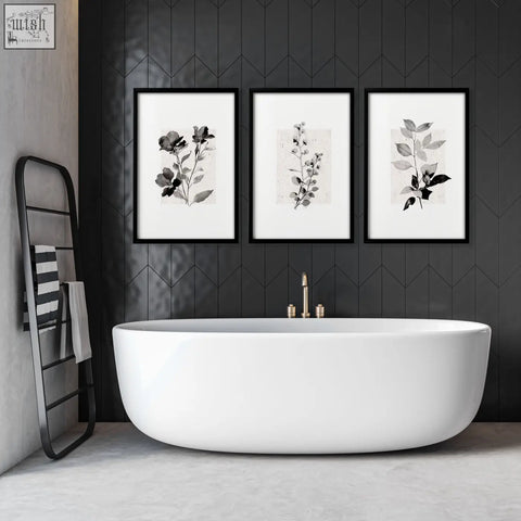Three black-framed beige wall art botanical pressed flower and leaf prints hang above a white bathtub