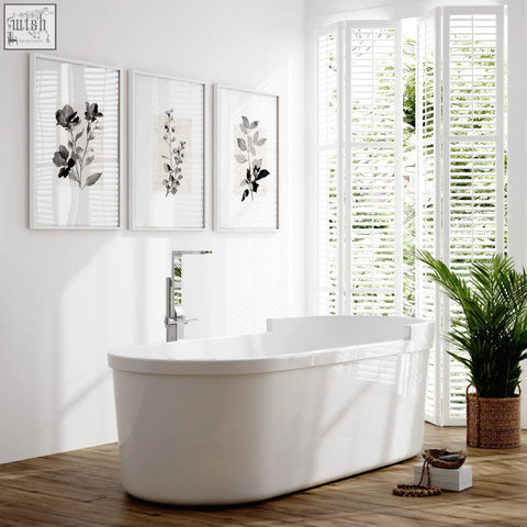 White freestanding bathtub with modern chrome faucet featured alongside beige wall art botanical pressed flower prints set of 3