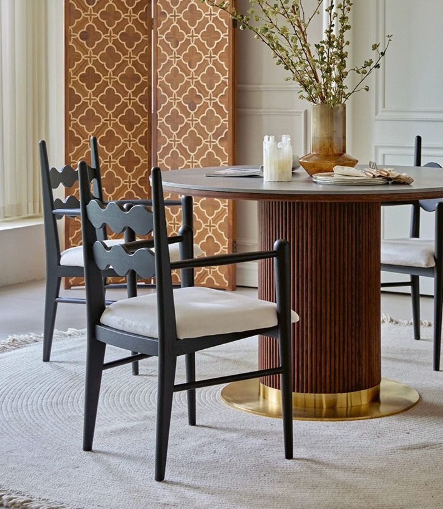 Black wooden dining chair with white upholstered seat and scalloped backrest paired with brown round dining table
