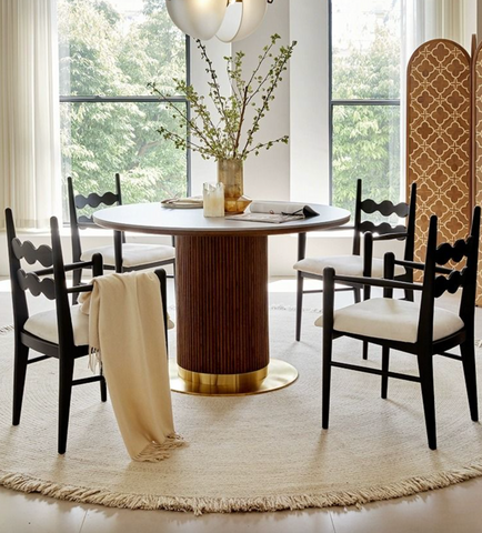 Bek round dining table in brown wood with gold-finished pedestal base and green branches centerpiece on top