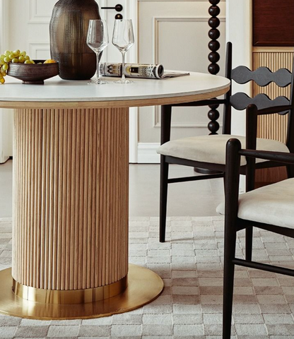 Bek round dining table with white top, fluted light wood base, and polished gold foot is a stylish round dining table