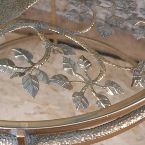 A belagavi gold round decorative glass-top coffee table with ornate metallic leaf and branch design in brushed gold finish