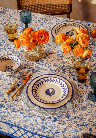 Blue and white ceramic dinner plate with scalloped edge and leafy border on belgravia bloom blue cotton tablecloth