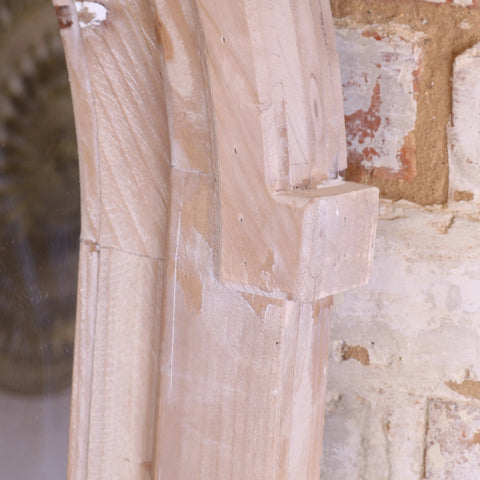 A light-colored wooden arch mirror with intricate carving and visible grain in a rustic finish perfect for decor